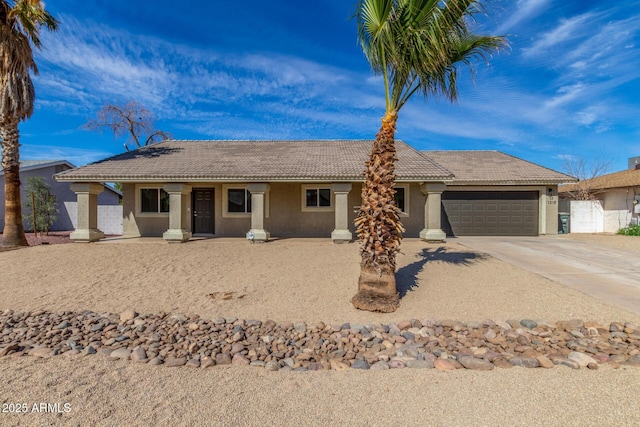 ranch-style house featuring an attached garage, a tile roof, concrete driveway, and stucco siding