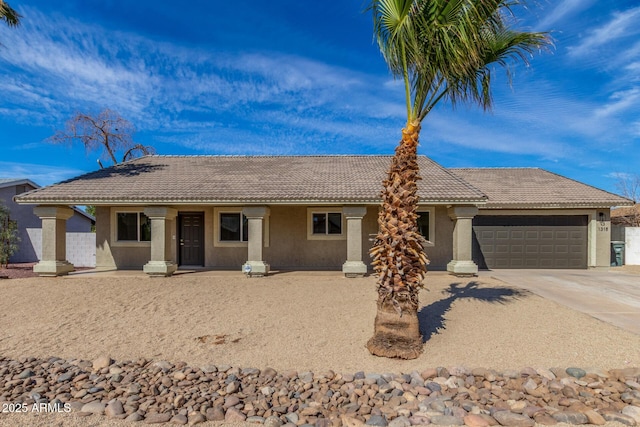 single story home with concrete driveway, a tiled roof, an attached garage, and stucco siding