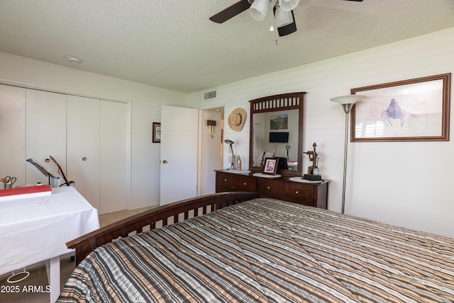 bedroom featuring ceiling fan, a textured ceiling, visible vents, and a closet