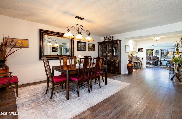 dining area with a textured ceiling, baseboards, and dark wood-type flooring