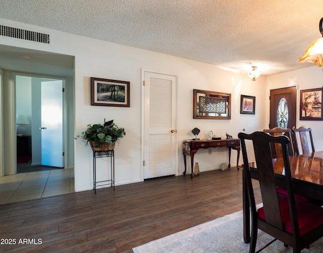 dining space featuring baseboards, visible vents, dark wood finished floors, and a textured ceiling