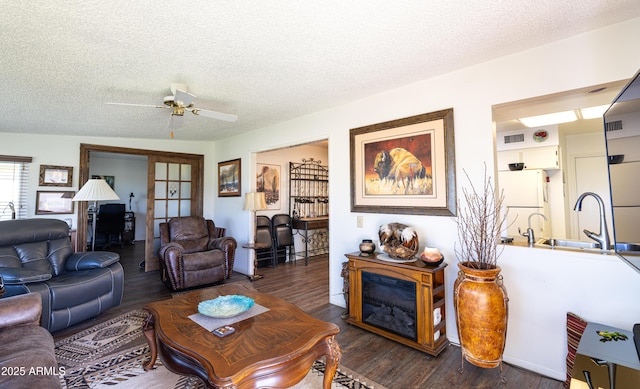 living area with dark wood-type flooring, visible vents, and a textured ceiling