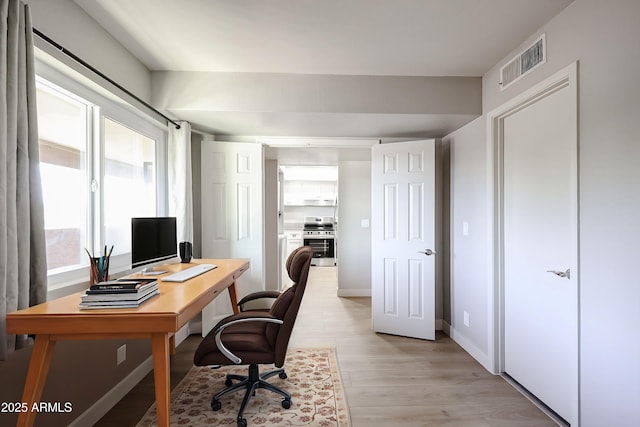 home office with light hardwood / wood-style flooring