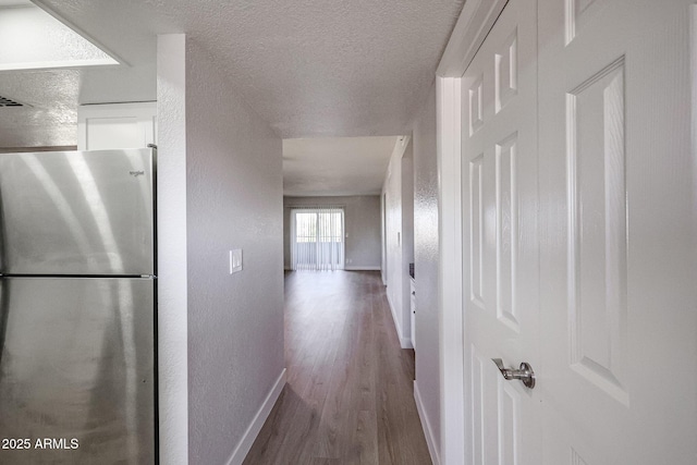 corridor with a textured ceiling and hardwood / wood-style flooring