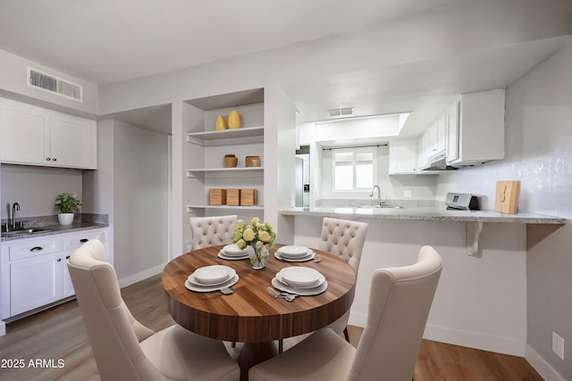 dining space featuring dark hardwood / wood-style floors, built in features, and sink