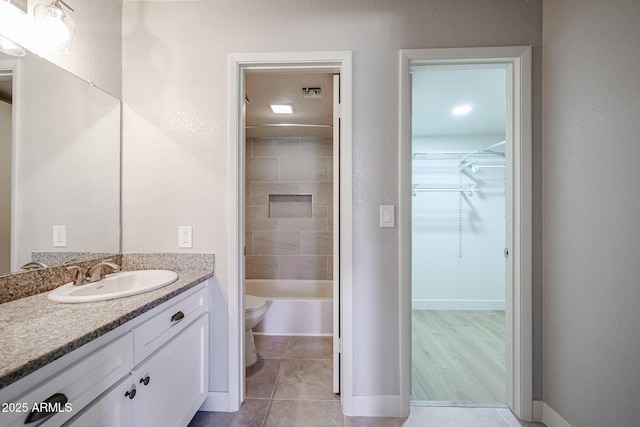 full bathroom with tile patterned floors, vanity, tiled shower / bath combo, and toilet