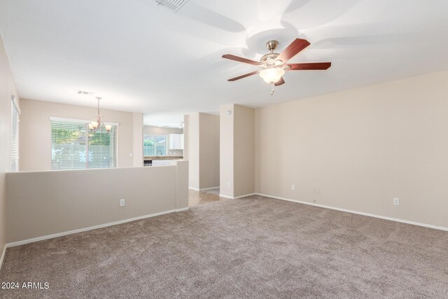 unfurnished room with ceiling fan with notable chandelier and light carpet