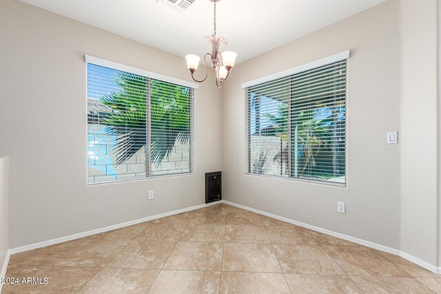 tiled spare room with a notable chandelier and plenty of natural light