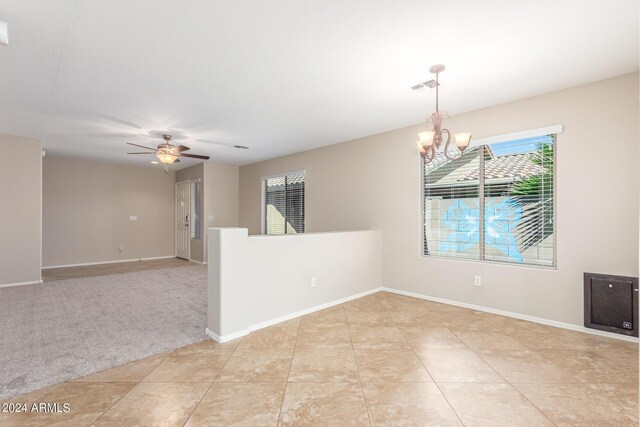 unfurnished room with ceiling fan with notable chandelier and light colored carpet