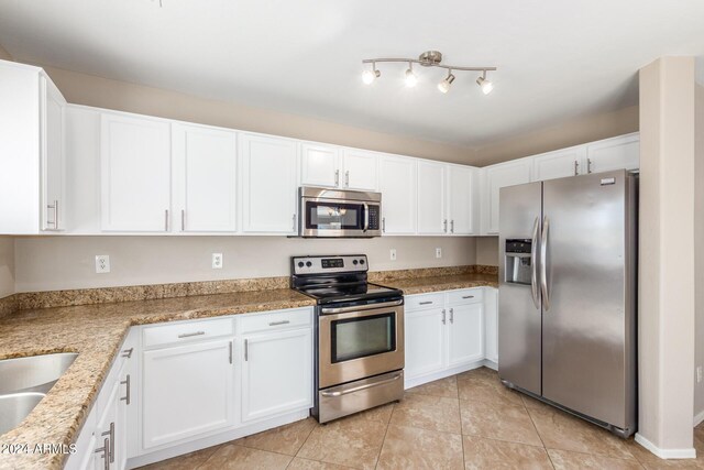 kitchen featuring light stone countertops, stainless steel appliances, white cabinetry, and light tile patterned flooring