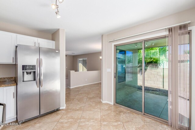 kitchen with stone counters, light tile patterned floors, white cabinetry, and stainless steel fridge with ice dispenser