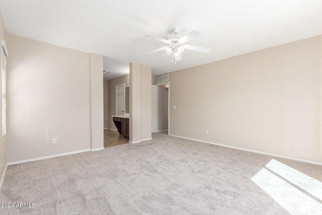 unfurnished bedroom with ceiling fan, light colored carpet, and ensuite bathroom