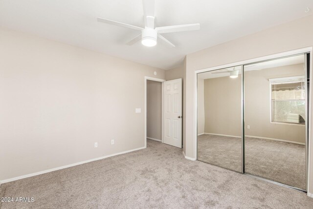 unfurnished bedroom featuring ceiling fan, light colored carpet, and a closet