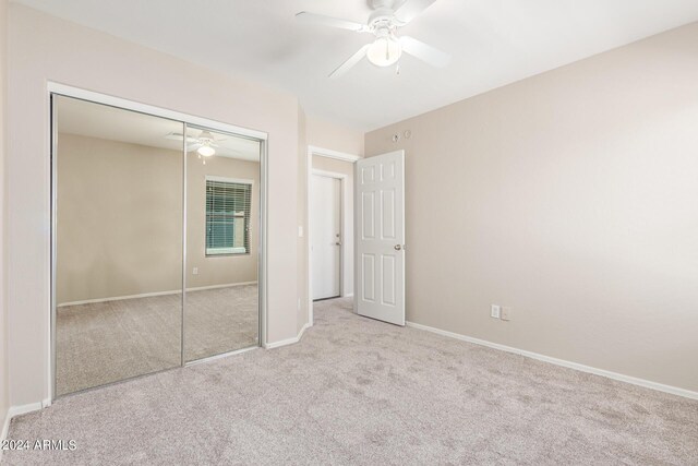 unfurnished bedroom featuring light carpet, a closet, and ceiling fan