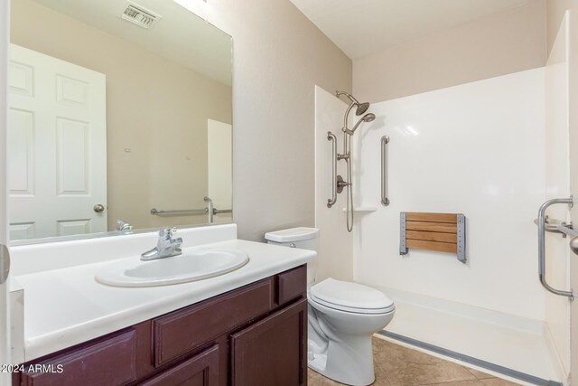 bathroom with tile patterned flooring, walk in shower, vanity, and toilet