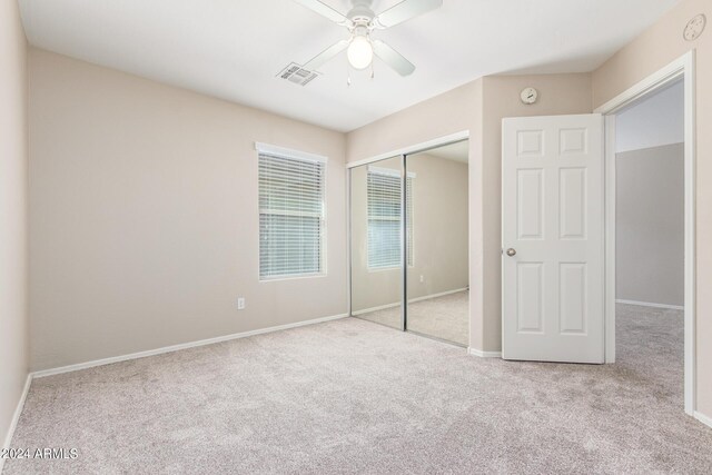 unfurnished bedroom with ceiling fan, light colored carpet, and a closet