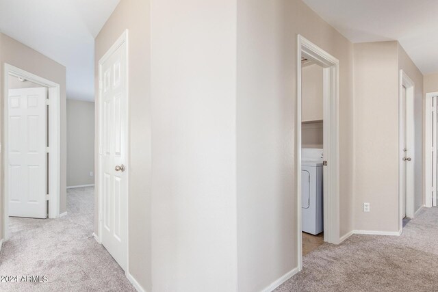 corridor featuring washer / clothes dryer and light carpet