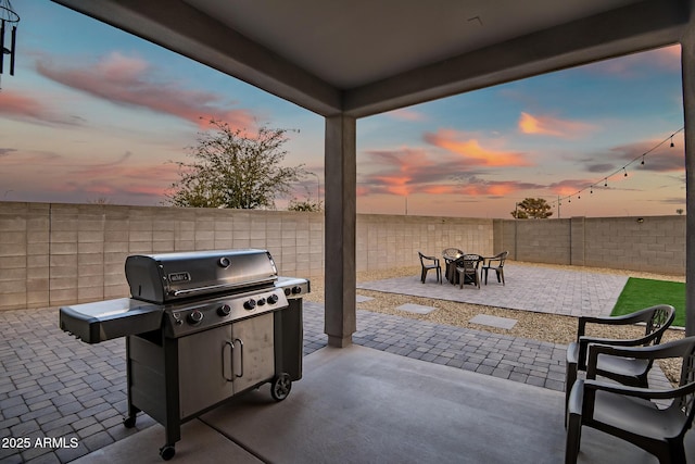 patio terrace at dusk featuring a grill