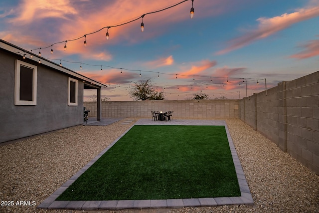 yard at dusk featuring a patio