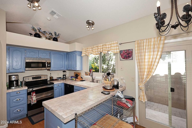 kitchen with dark wood-type flooring, kitchen peninsula, sink, vaulted ceiling, and appliances with stainless steel finishes