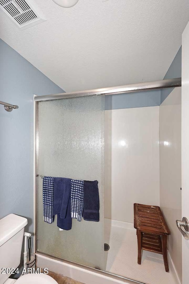 bathroom with a shower with door and toilet