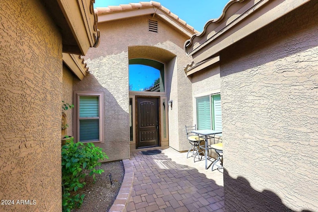 view of exterior entry with a patio area