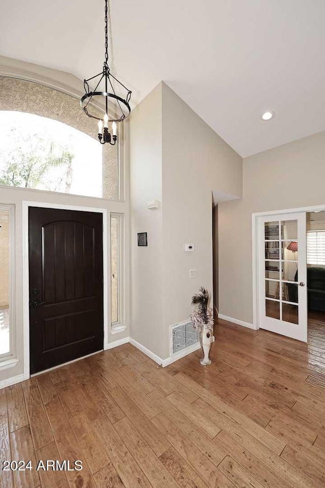 foyer entrance featuring french doors, hardwood / wood-style floors, and a chandelier