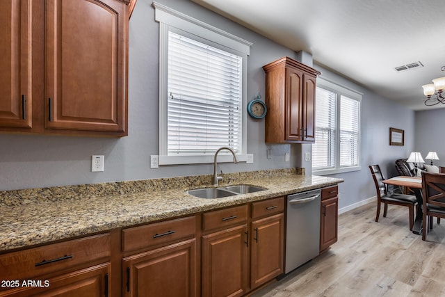 kitchen with light stone counters, dishwasher, sink, and light hardwood / wood-style flooring