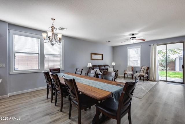 dining room featuring ceiling fan with notable chandelier and light hardwood / wood-style flooring