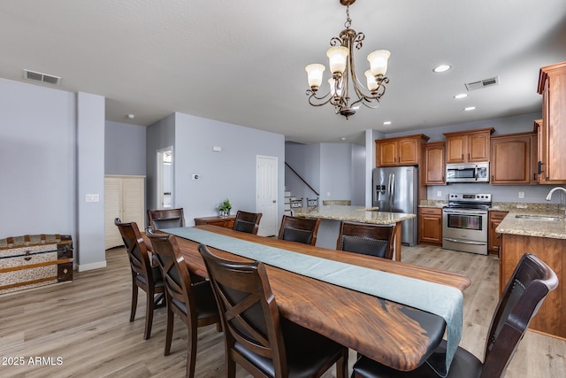 kitchen with sink, decorative light fixtures, light hardwood / wood-style flooring, a kitchen island, and stainless steel appliances