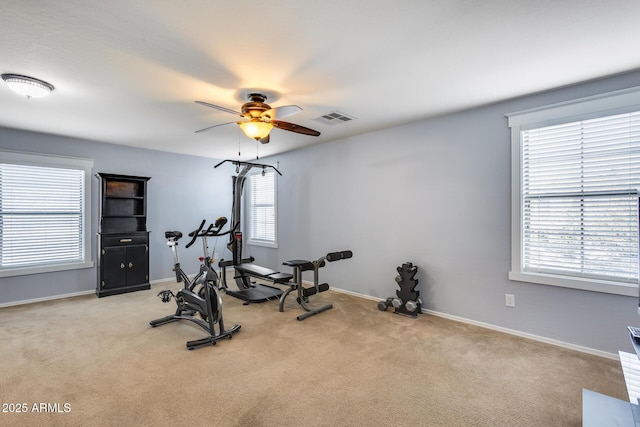 exercise area featuring ceiling fan, light colored carpet, and plenty of natural light