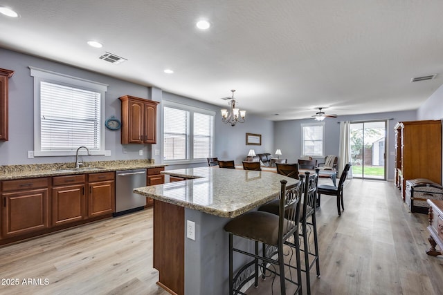 kitchen featuring a breakfast bar, pendant lighting, dishwasher, sink, and a center island