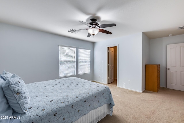 bedroom with ceiling fan, light colored carpet, and a spacious closet