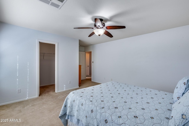 carpeted bedroom with a walk in closet, a closet, and ceiling fan