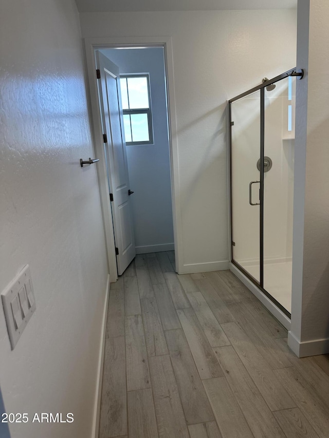 bathroom featuring a shower stall, baseboards, and wood finished floors