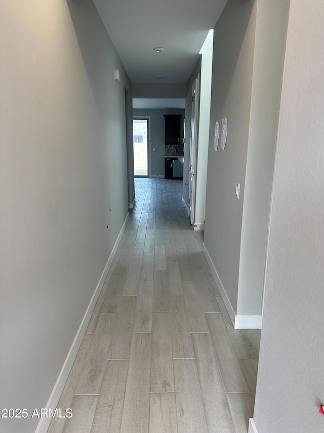 corridor with light wood-style flooring and baseboards