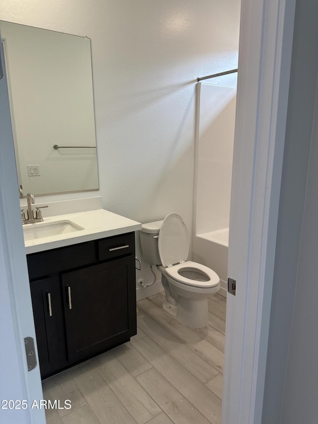 full bathroom with toilet, walk in shower, wood finished floors, and vanity