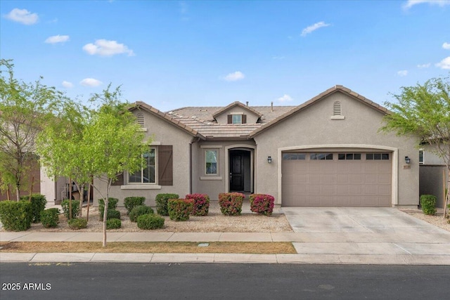 view of front of home with a tiled roof, an attached garage, driveway, and stucco siding