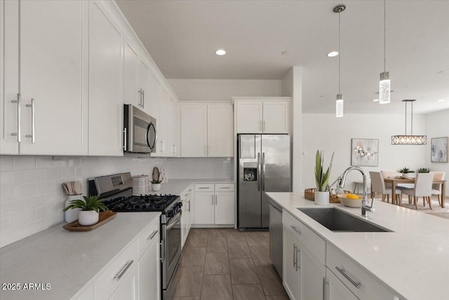 kitchen featuring a sink, decorative light fixtures, white cabinetry, appliances with stainless steel finishes, and decorative backsplash