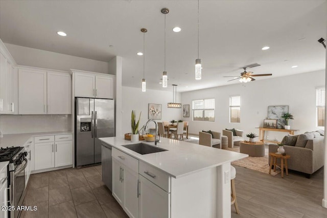 kitchen with open floor plan, light countertops, appliances with stainless steel finishes, white cabinets, and a sink