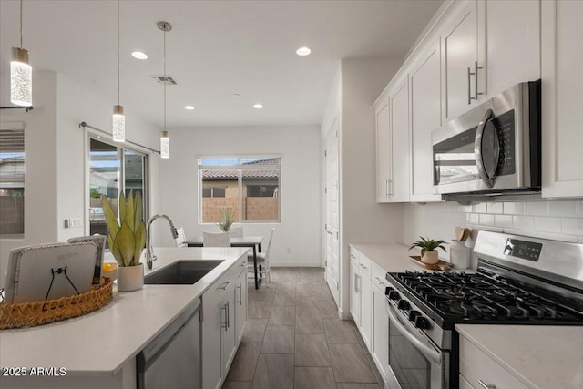 kitchen featuring visible vents, a sink, stainless steel appliances, white cabinets, and backsplash