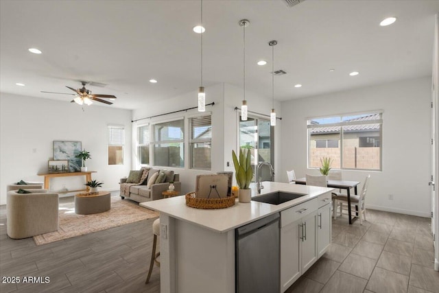 kitchen with a sink, visible vents, light countertops, stainless steel dishwasher, and a kitchen island with sink