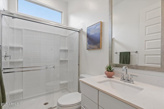 bathroom featuring vanity, a shower stall, and toilet