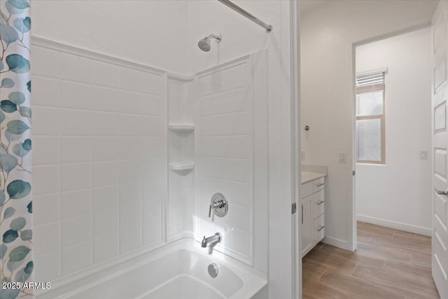 bathroom with wood finish floors, baseboards, shower / tub combo with curtain, and vanity