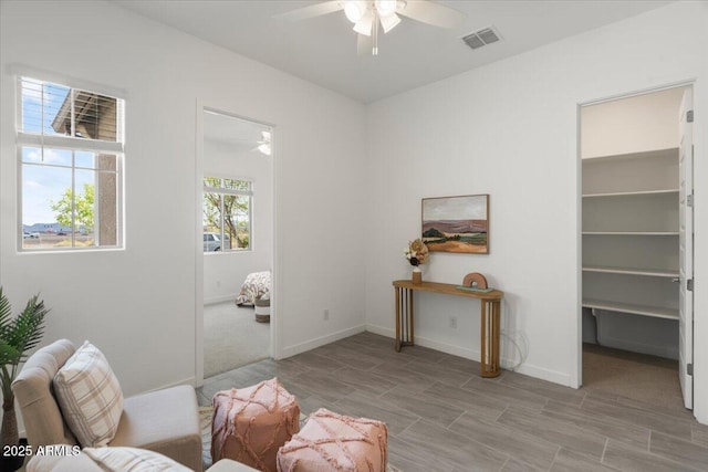 sitting room with visible vents, baseboards, and ceiling fan