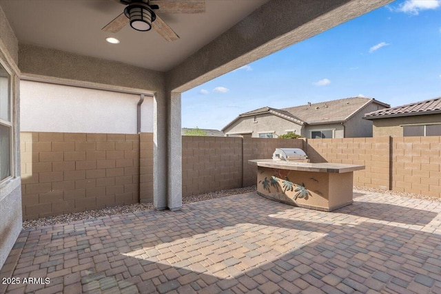 view of patio featuring an outdoor kitchen, a grill, a fenced backyard, and ceiling fan