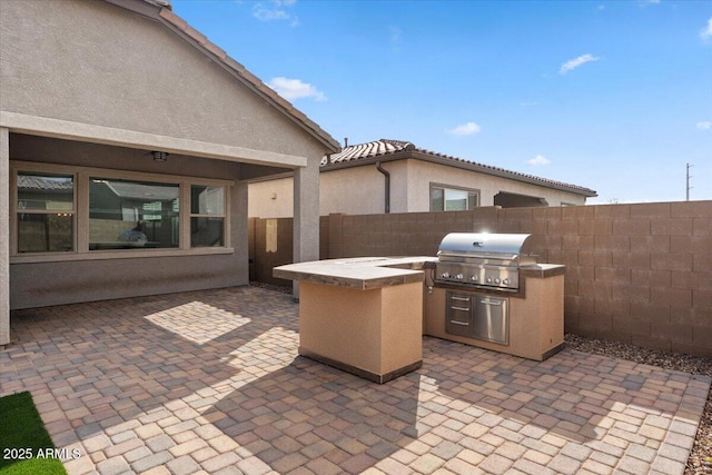 view of patio with an outdoor kitchen, a fenced backyard, and a grill