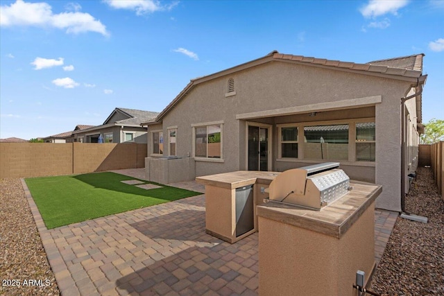 rear view of house with a patio area, area for grilling, stucco siding, and a fenced backyard