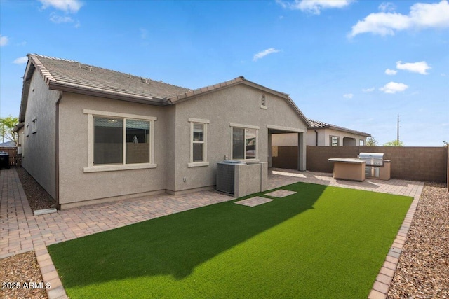 rear view of property with stucco siding, a patio, a fenced backyard, and exterior kitchen