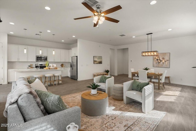 living area with baseboards, visible vents, recessed lighting, ceiling fan, and light wood-type flooring